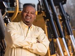 Man smiling in front of tractors